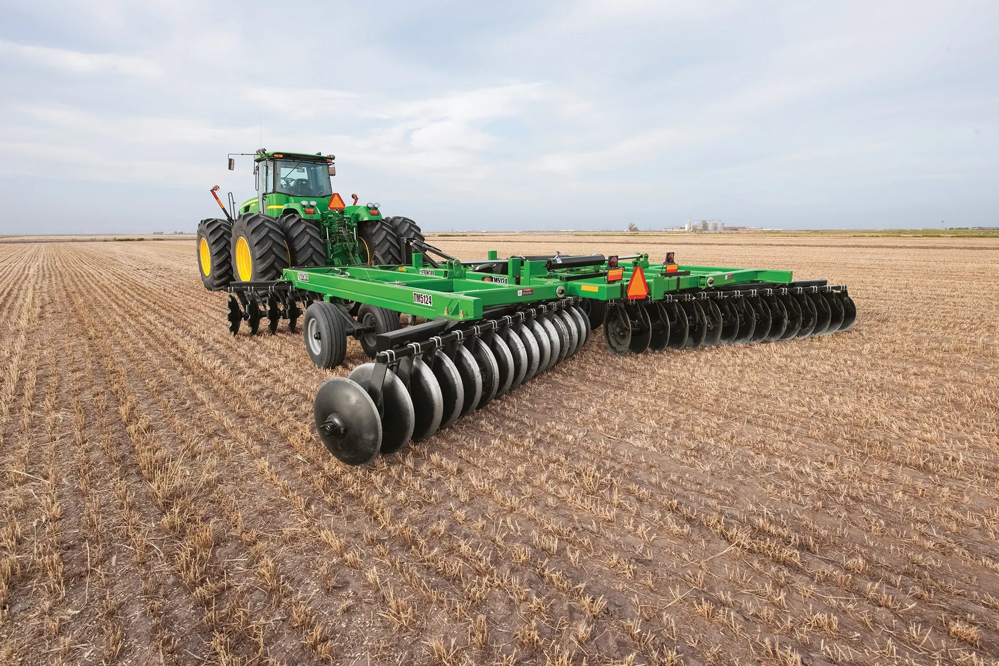 Left rear view of a tractor pulling a Frontier Tandem 51 Series Disk Harrow in the field