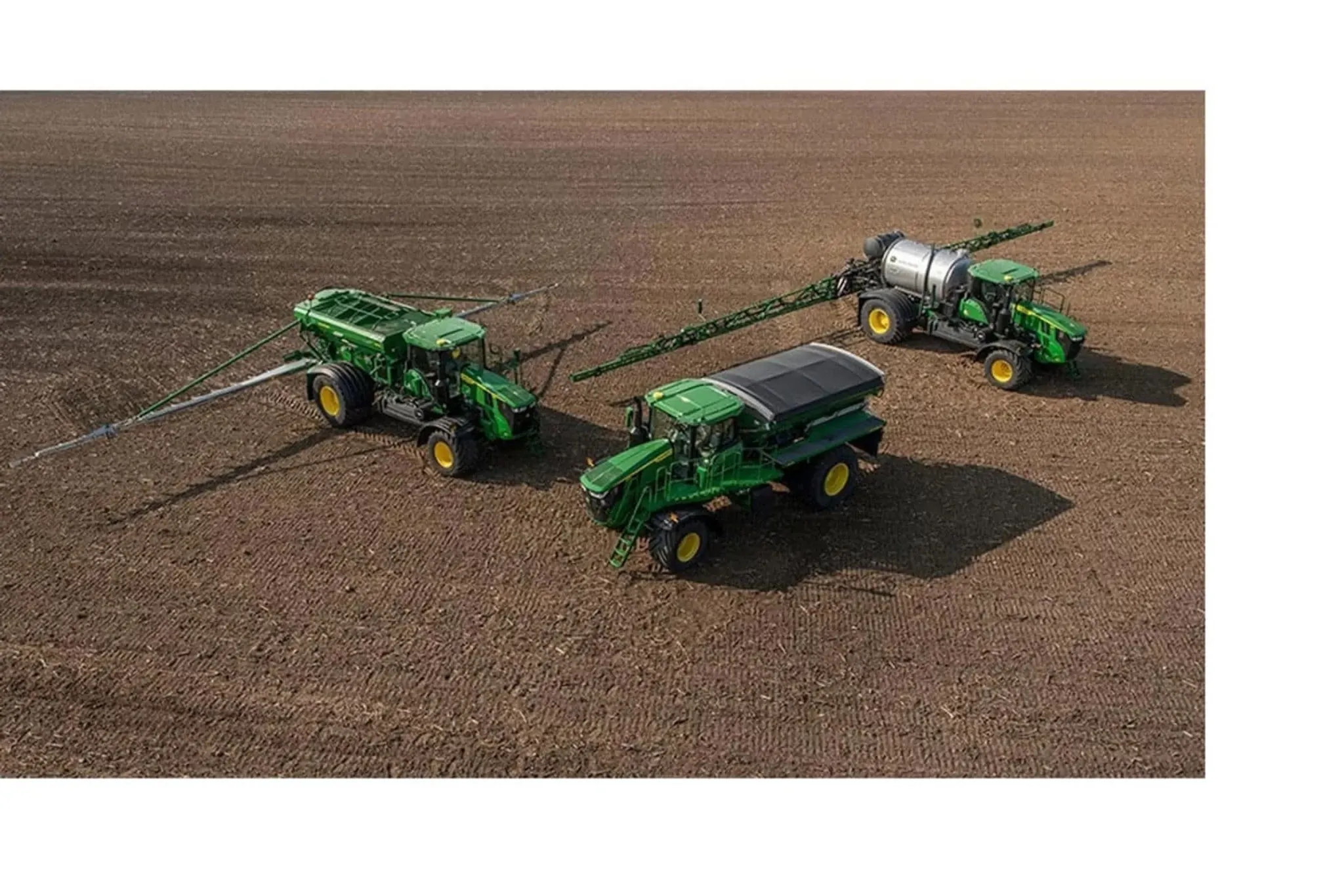 Two sprayers and a grain cart in a planted field
