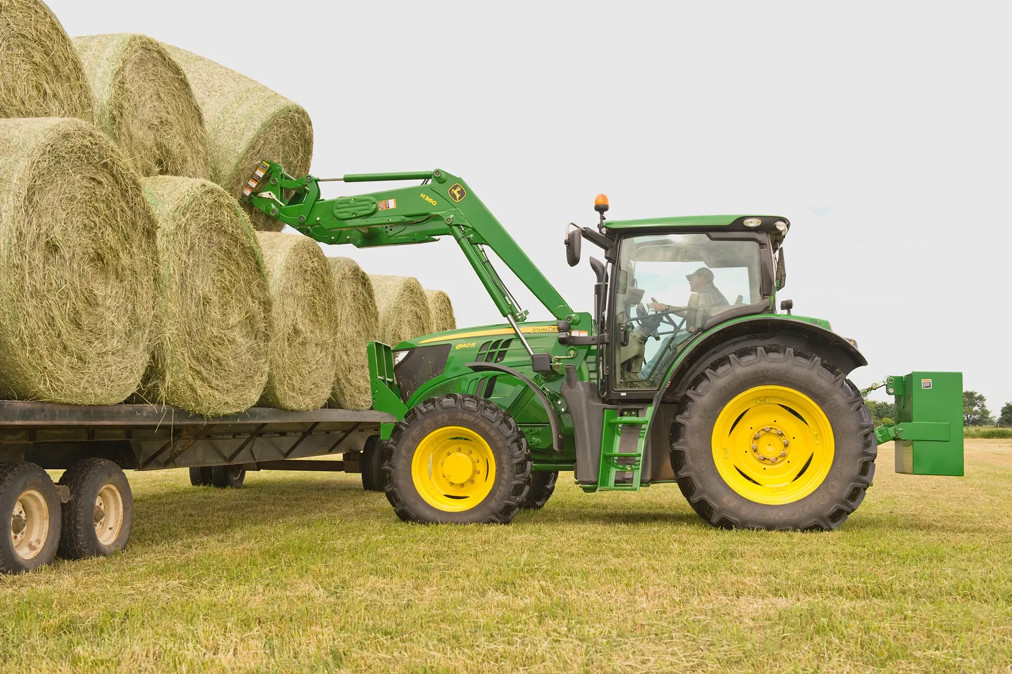 6140R Tractor with AB12G Bale Spear loading round bale onto a flatbed