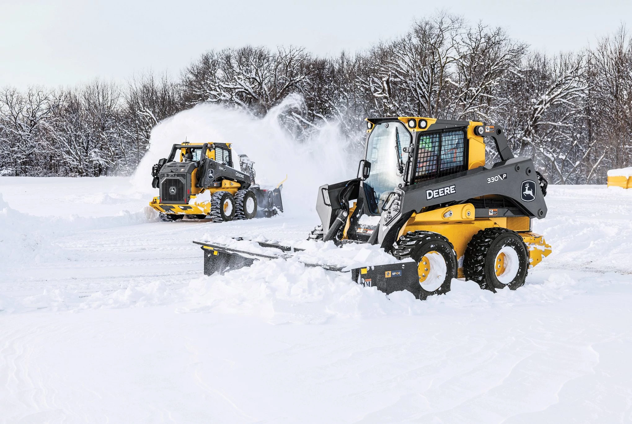 334 P-Tier skid steer loaders clear snow in an open area covered in deep white snow.