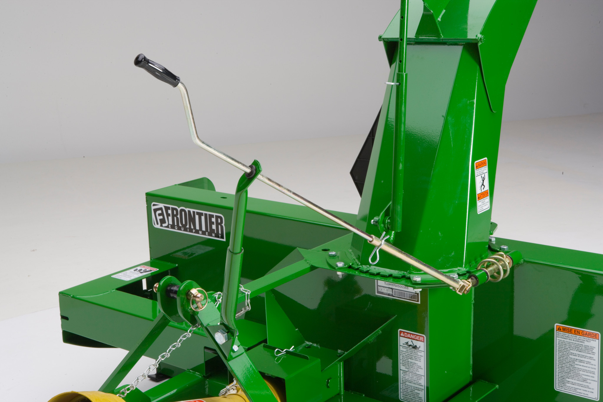 Close-up of snowblower showing a metal control lever and linkage mounted beside the discharge chute