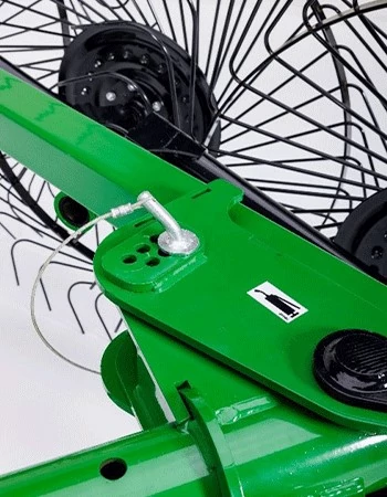 Close-up studio view of the adjustment point on green wheel rake bar with circular rake in the background