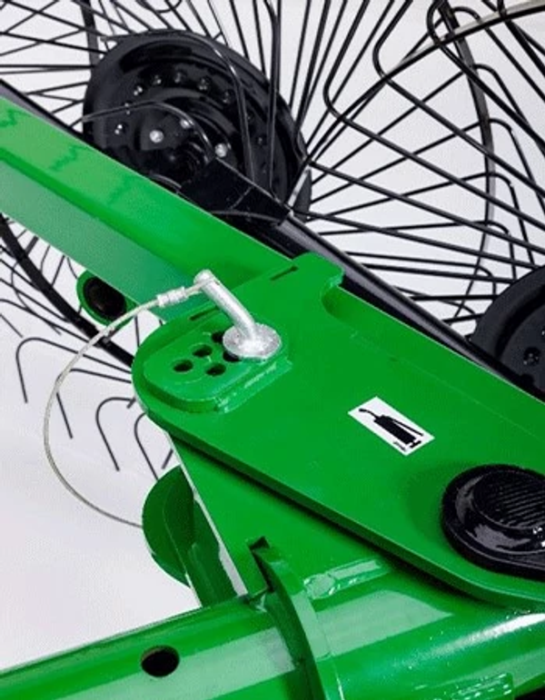 Close-up studio view of the adjustment point on green wheel rake bar with circular rake in the background