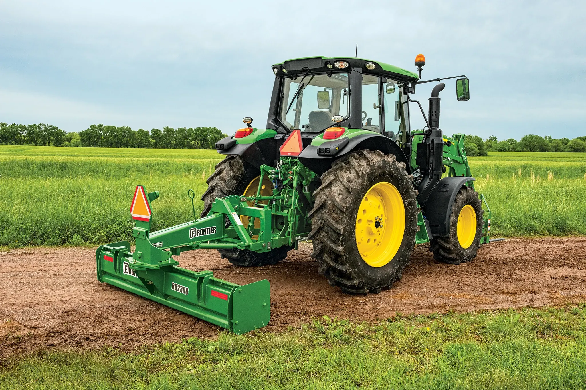 Field view of 6120M Tractor with RB2308 Rear Blade on dirt path
