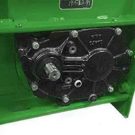 A close-up view of a black gearbox mounted inside a green equipment housing, showing bolts and a protruding shaft