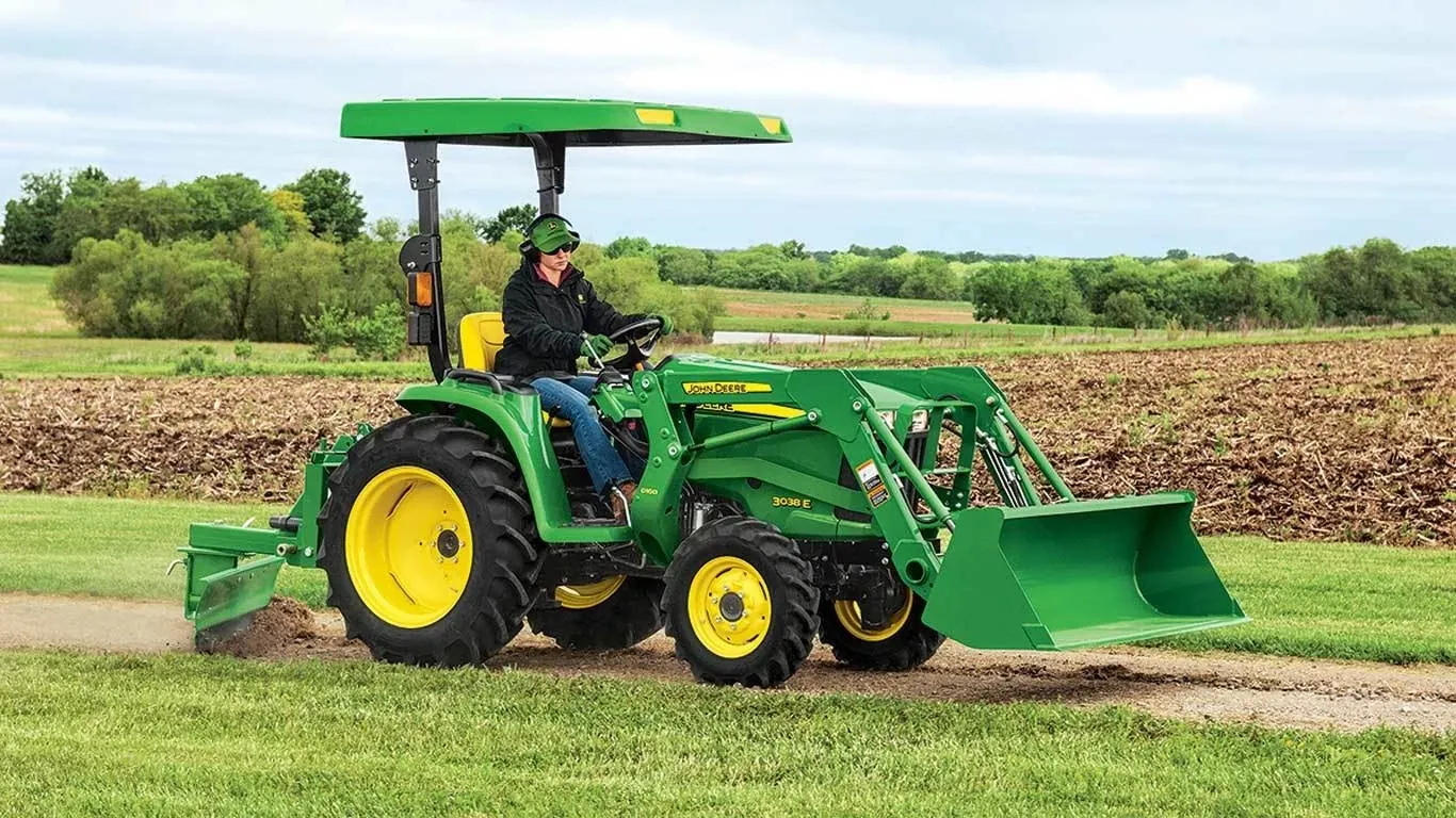 Farmer driving a tractor with a Frontier RB20 rear blade down a dirt road