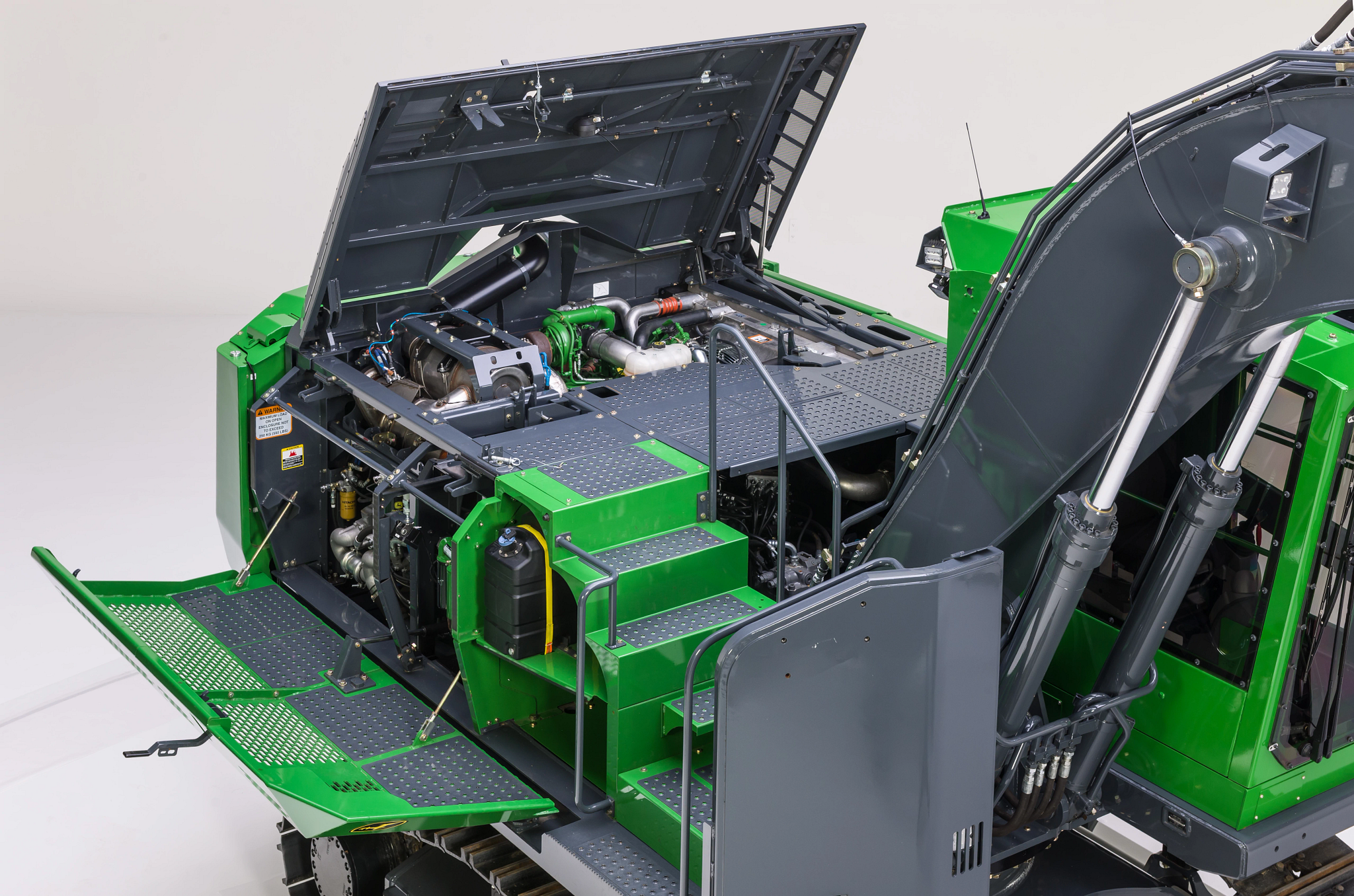 Industrial machine with open access panels revealing the engine compartment, hydraulic components, steps, and service platforms.