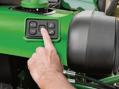 Image of someone pressing the hitch assist on a compact tractor