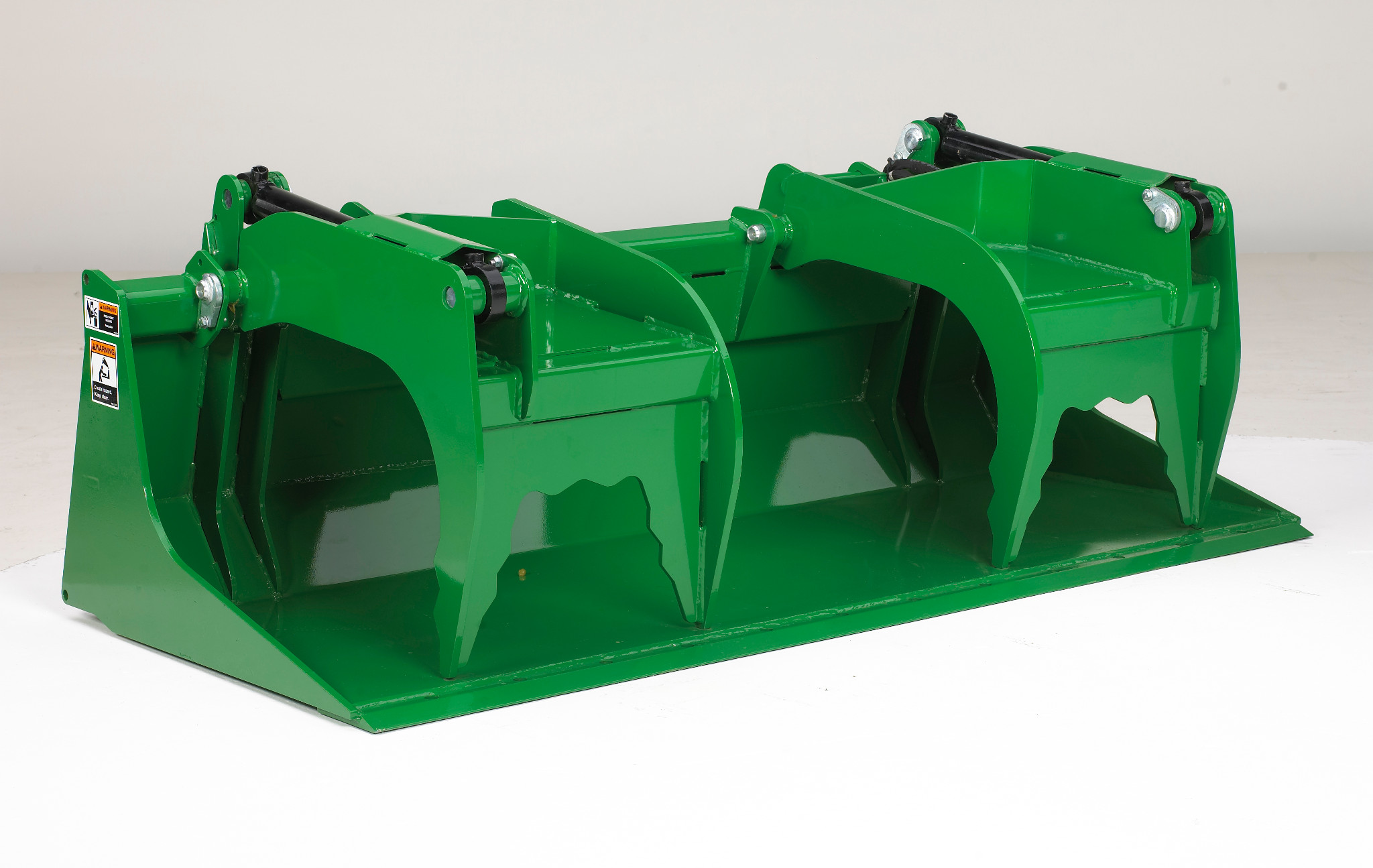 Green dual‑clamp grapple attachment with two curved upper jaws and a wide lower bucket edge, shown on a white background
