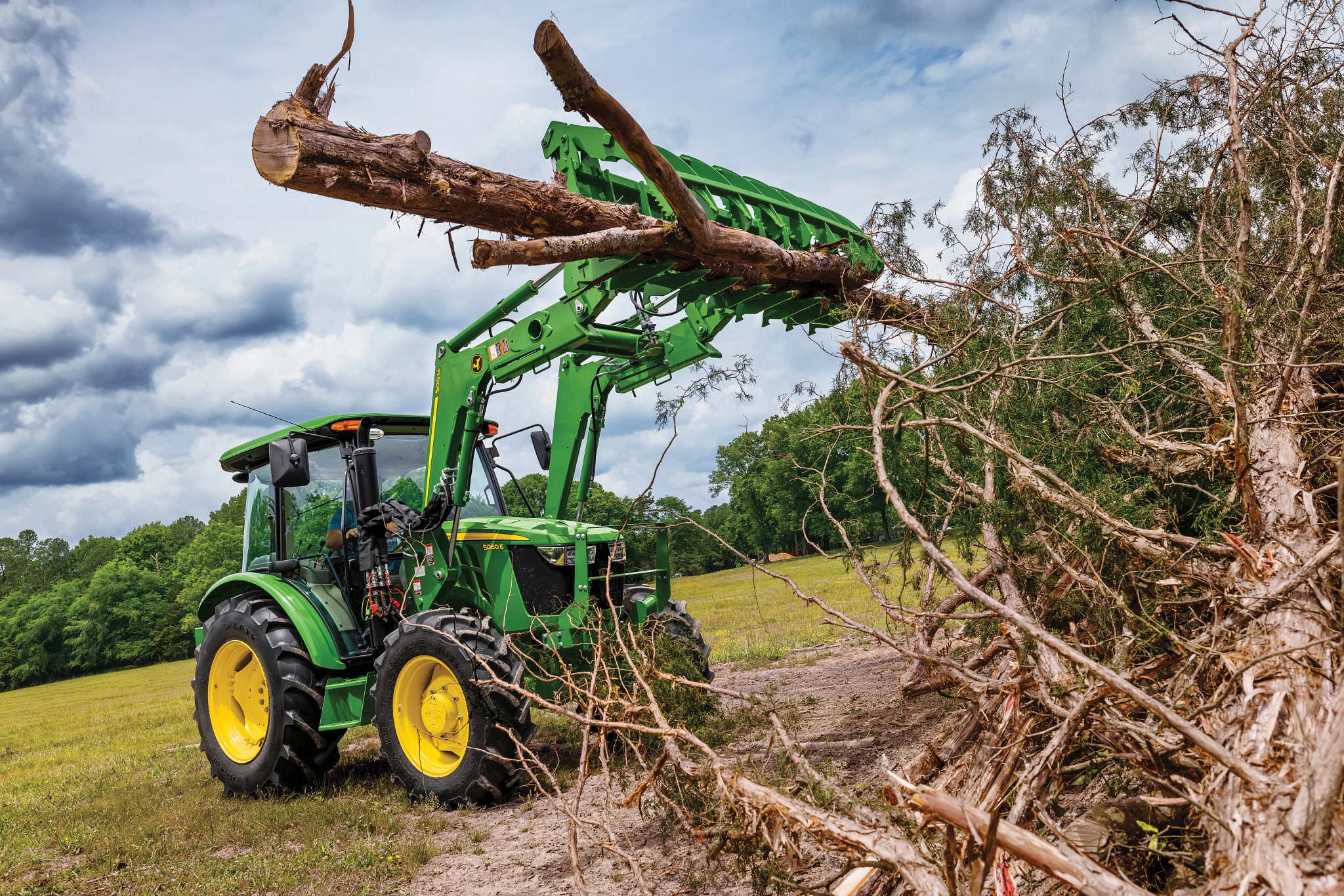 Field view of AV50 Root Grapple on 5E Tractor with log in the air