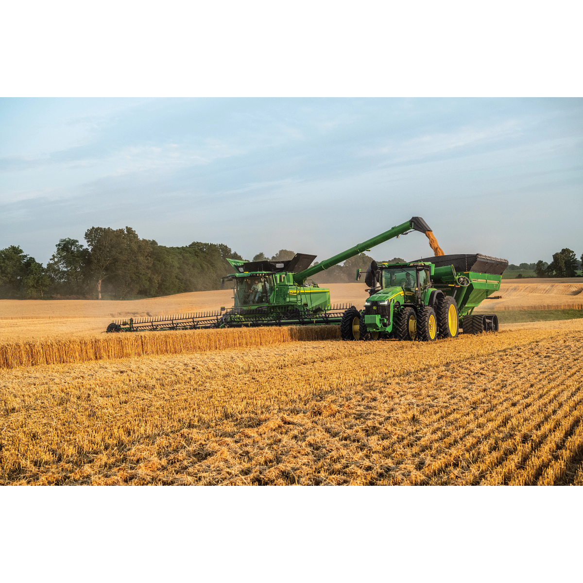 John Deere combine unloading into a grain cart during harvest — Koenig Equipment