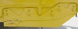 Close-up of a yellow metal machine component with bolts and reinforced edges, showing embossed markings on the side surface