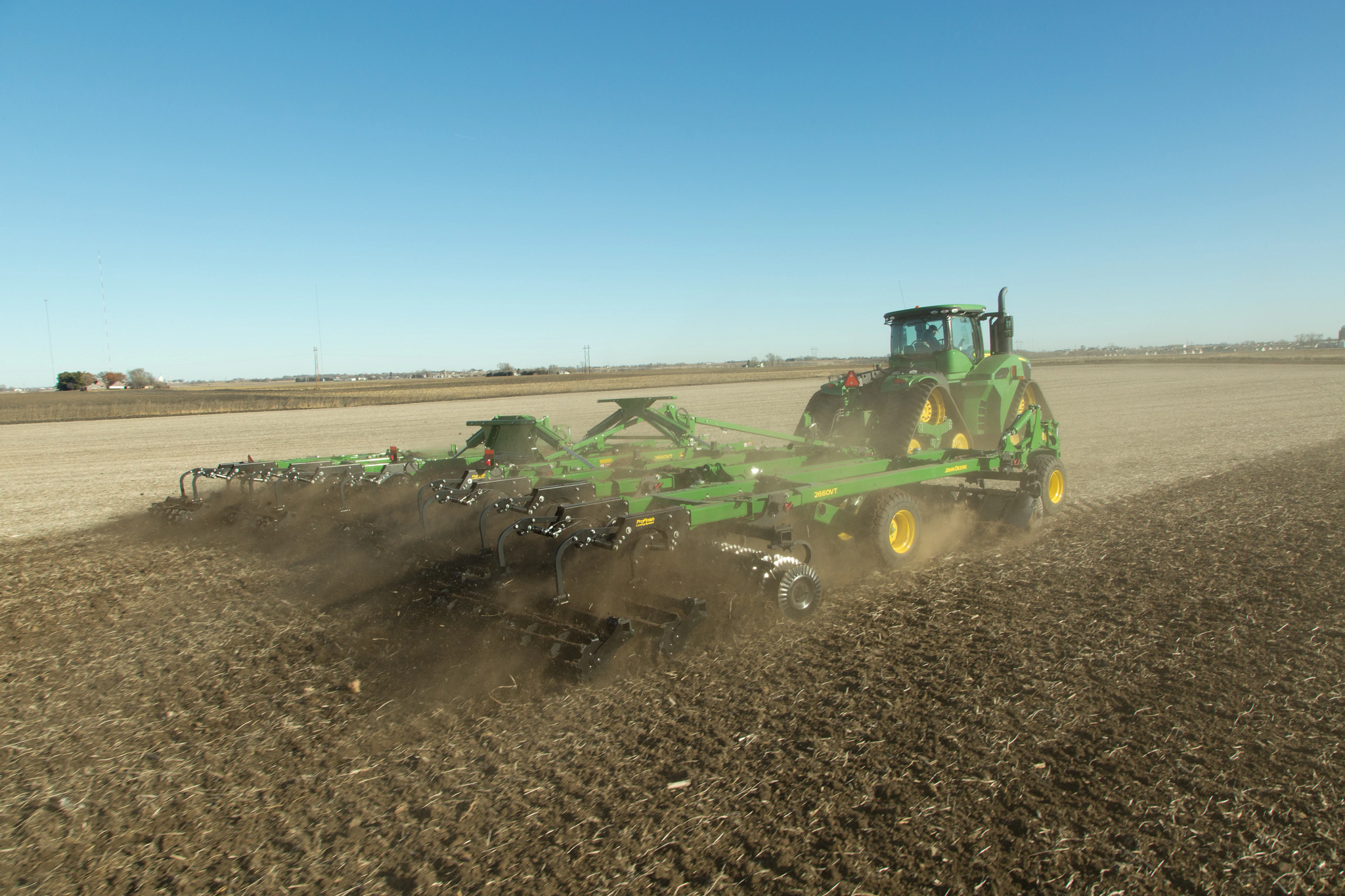 Rear right view of a 9RX series tractor with StarFire 6000 pulling a 2660VT Variable Intensity Tillage implement across a brown field