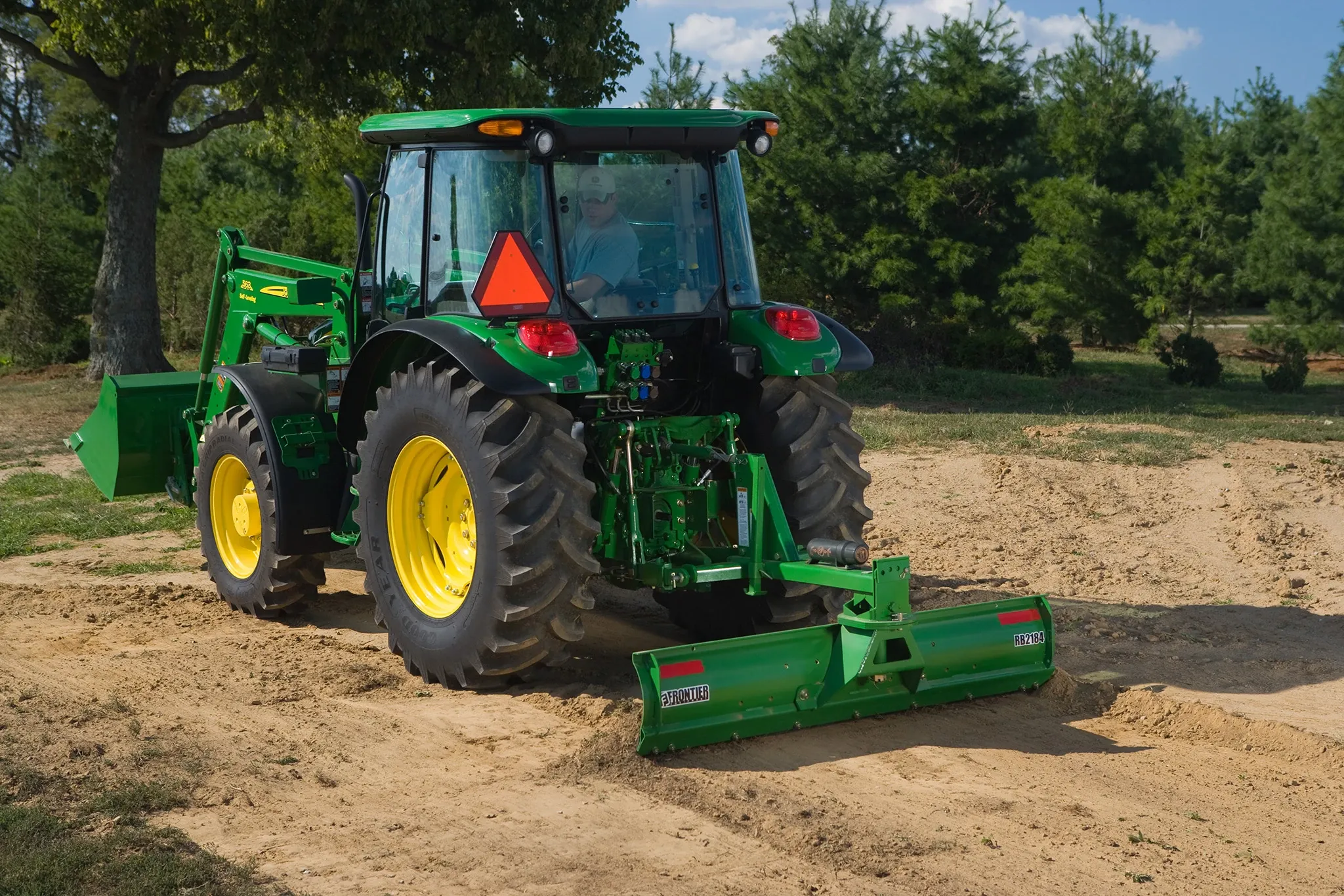 Field view of 5095M Tractor with RB2184 Front Blade moving dirt