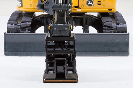 Front studio view of the bottom of an excavator with attached PC plate compactor resting on the floor