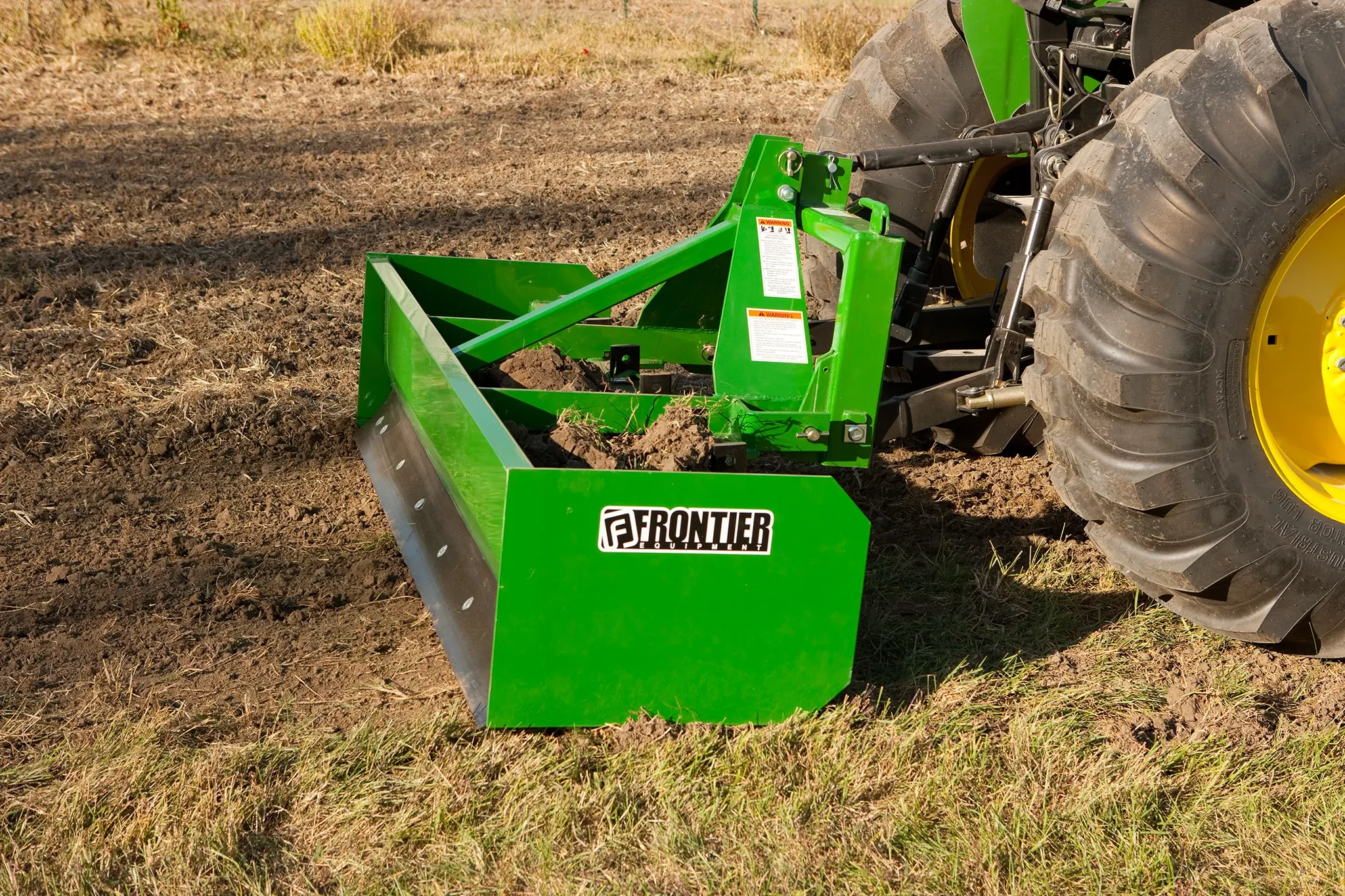 Box blade on utility tractor in field