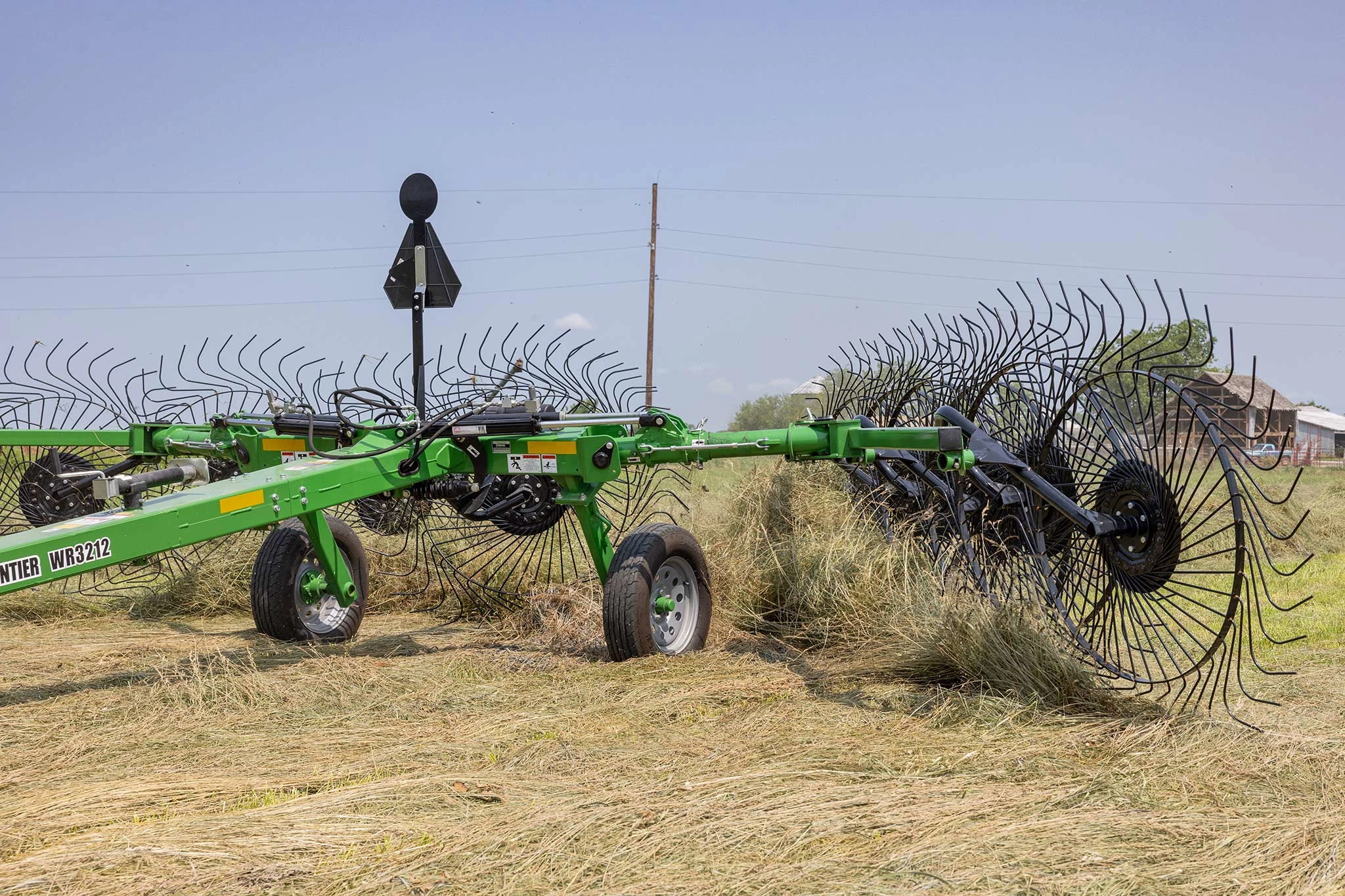 Side left view of a WR3212 wheel rake at work on hay in a field