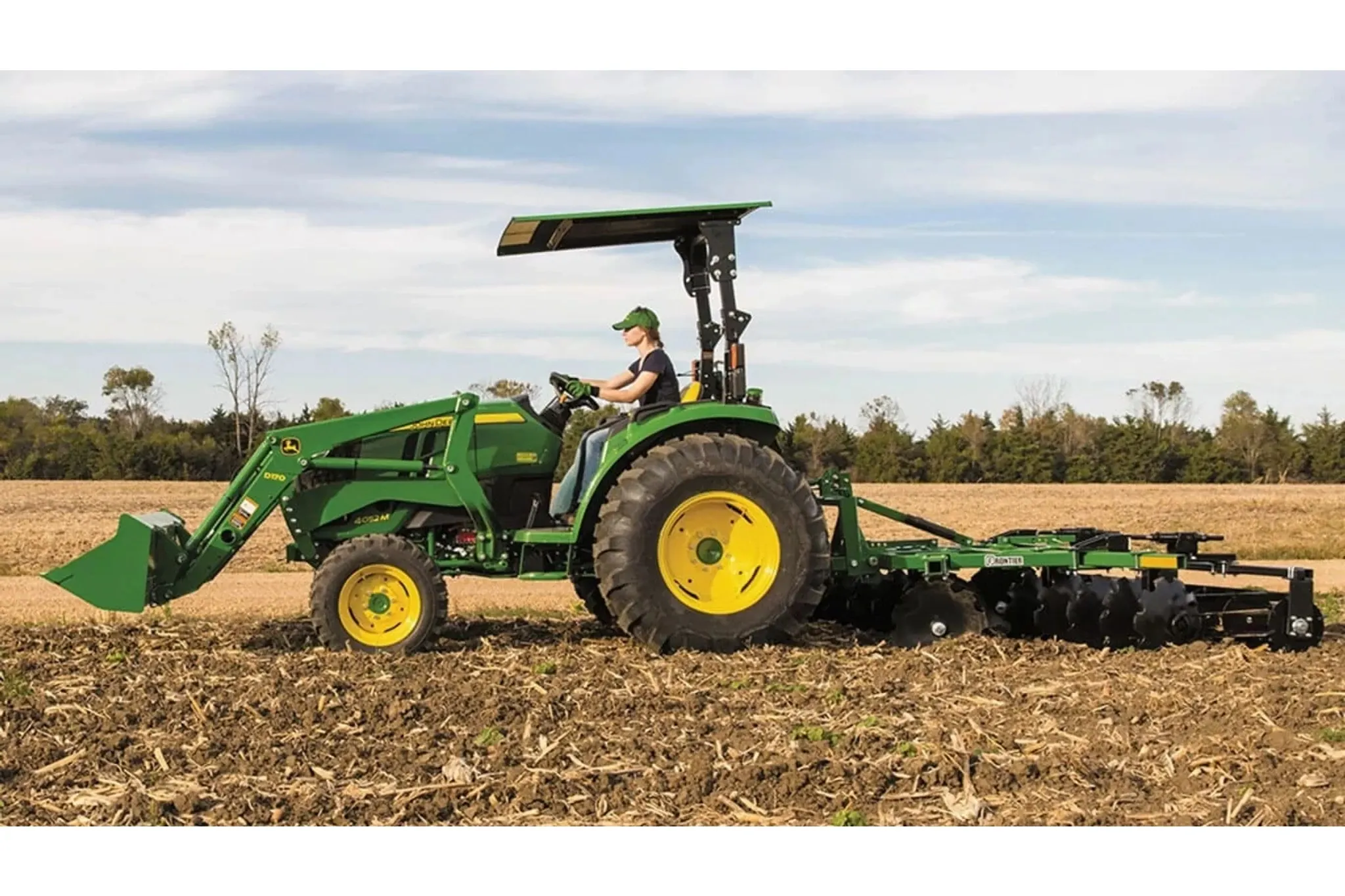 farmer tilling a corn field using a 4052M Compact Tractor with a tillage attachment