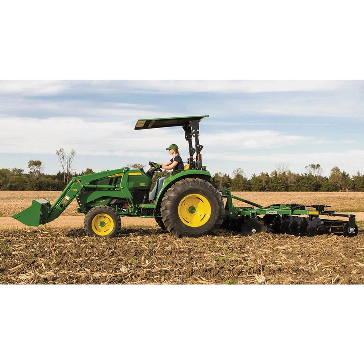 farmer tilling a corn field using a 4052M Compact Tractor with a tillage attachment