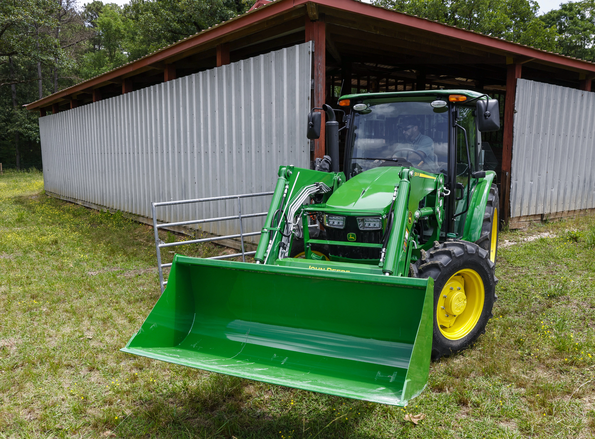 Front view of a 5060E Tractor exiting a barn with 500M Loader attached