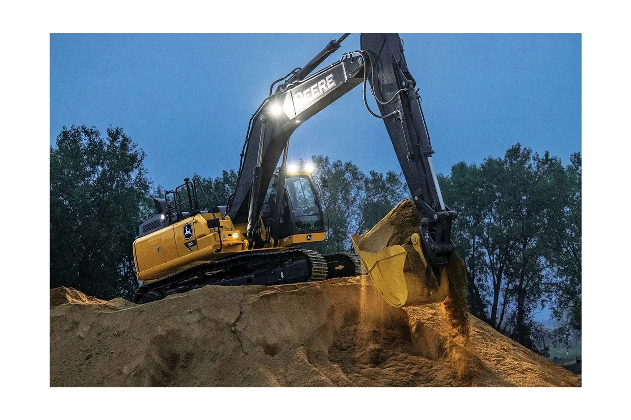 380 P-Tier Compact Excavator on a jobsite at night with lights on