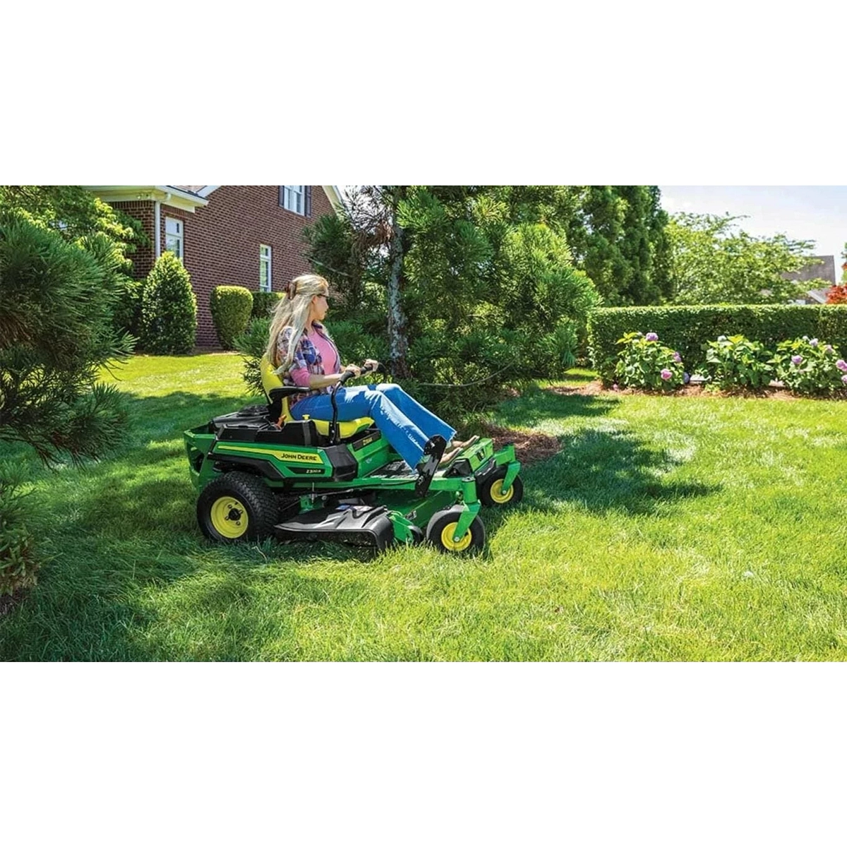 Homeowner mowing between plants and trees with a John Deere Z320R ZTrak mower — Koenig Equipment