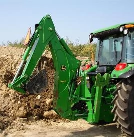 Side right view of a 959 backhoe's back end, boom, and bucket in front of a dirt and grass hill