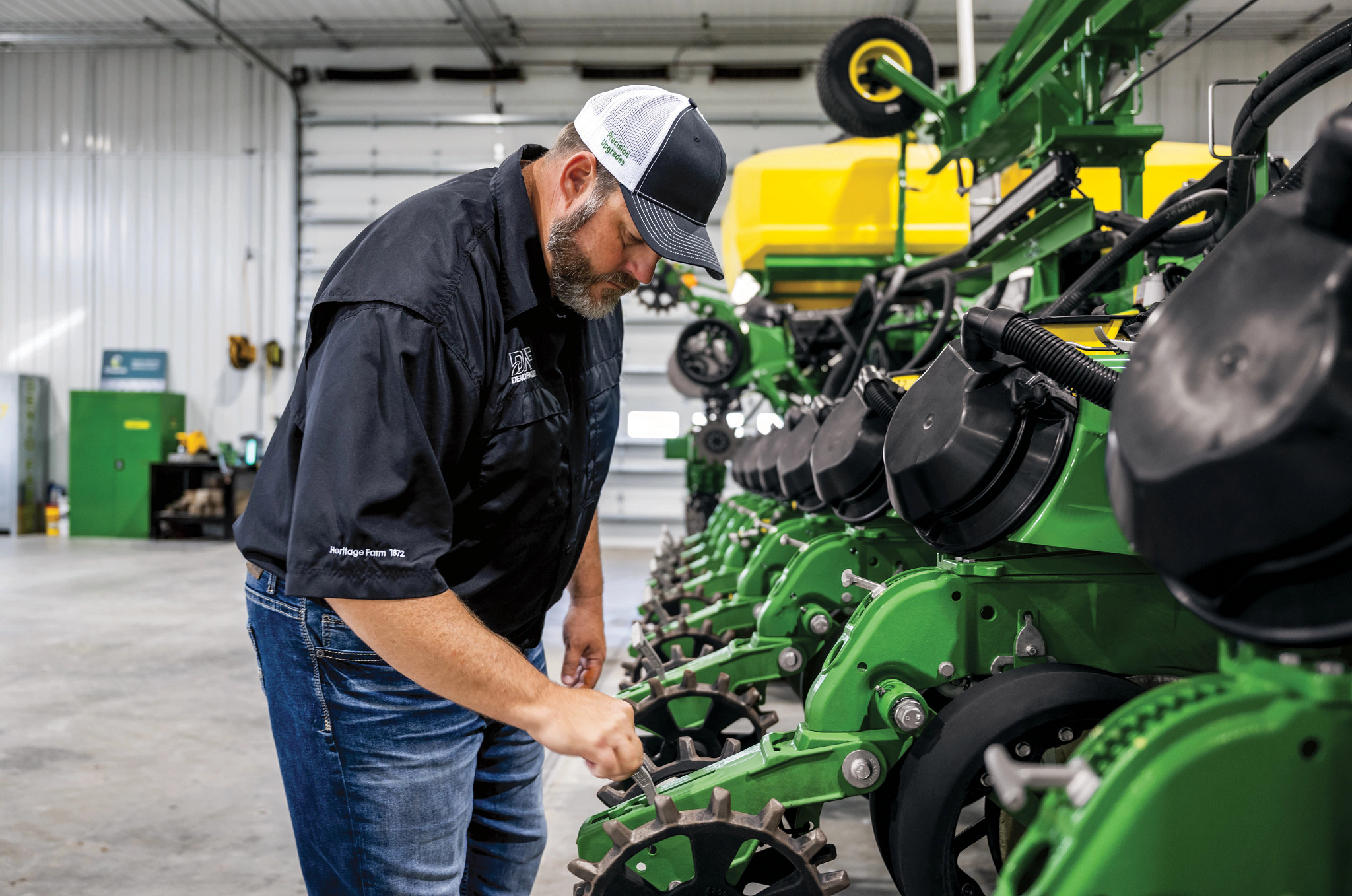 Farmer checking a John Deere planter row unit in a workshop