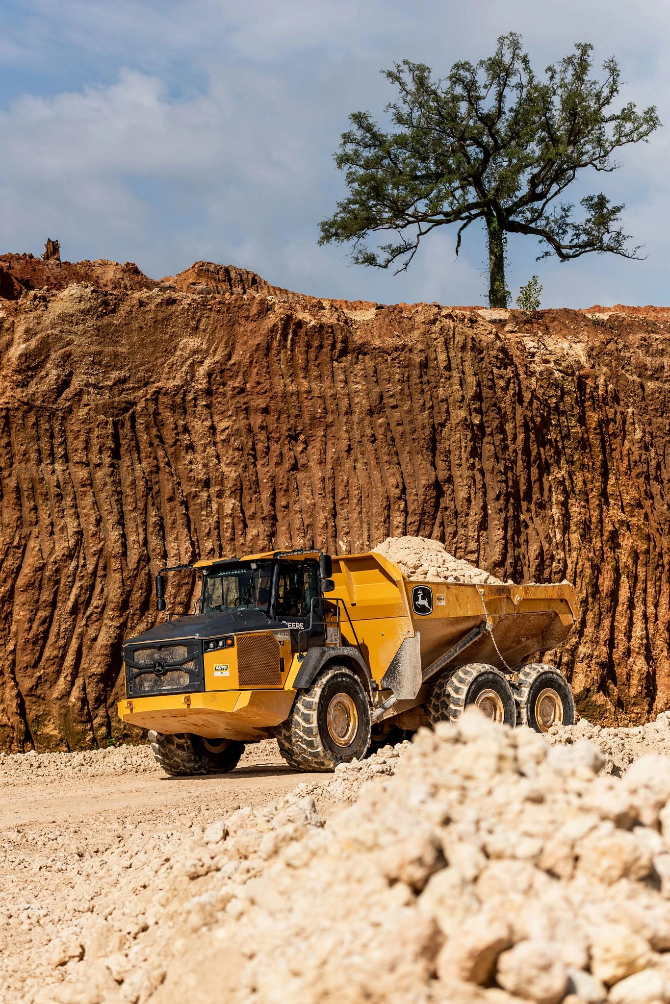 John Deere articulated dump truck hauling gravel through a mining worksite