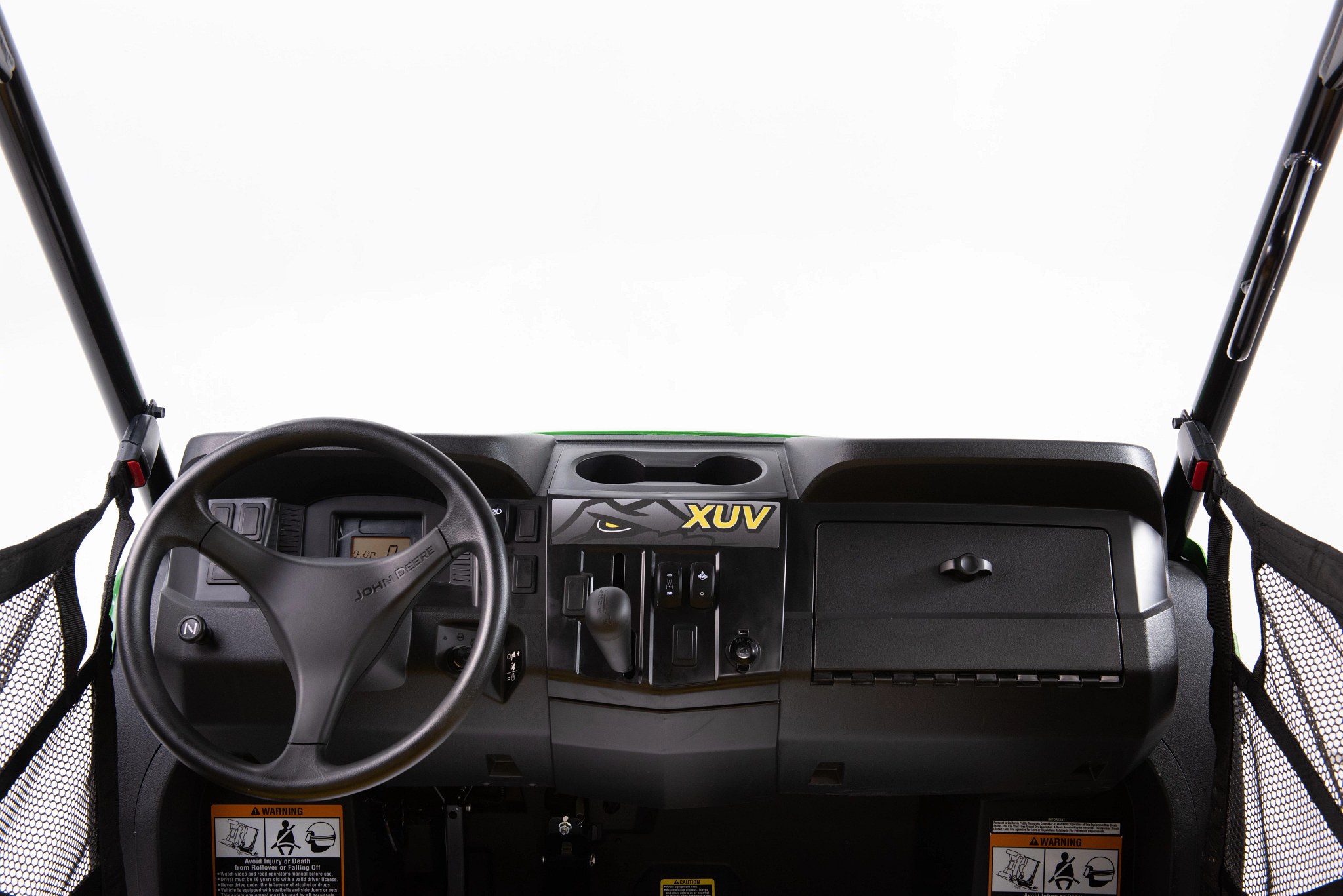 A straight-on view of the dashboard and steering wheel of a John Deere XUV, showing central controls, gauges, a storage compartment, and mesh doors