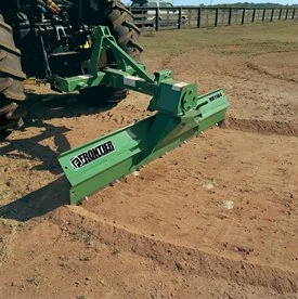 Front right view of a rear blade attached to tractor pulling dirt at an angle