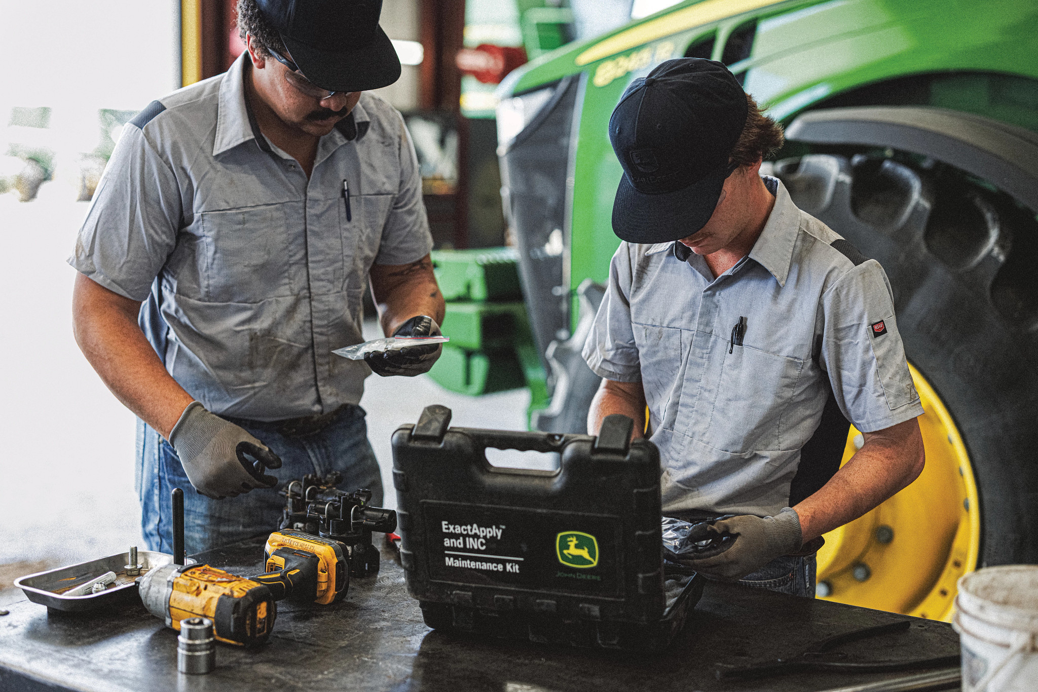 John Deere service technicians preparing tools beside a tractor