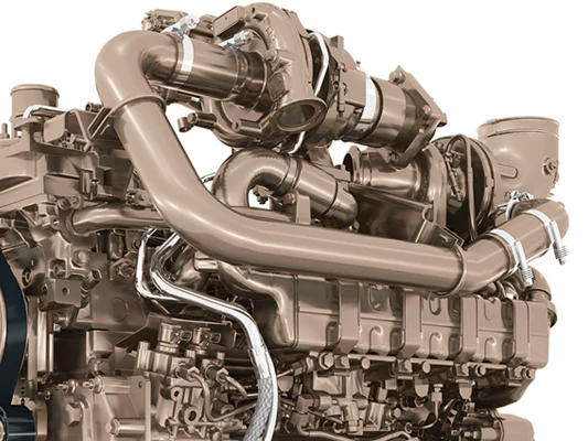 Close-up of a large industrial engine with prominent curved intake and exhaust pipes, turbocharger assemblies, and interconnected metal tubing, shown against a white background