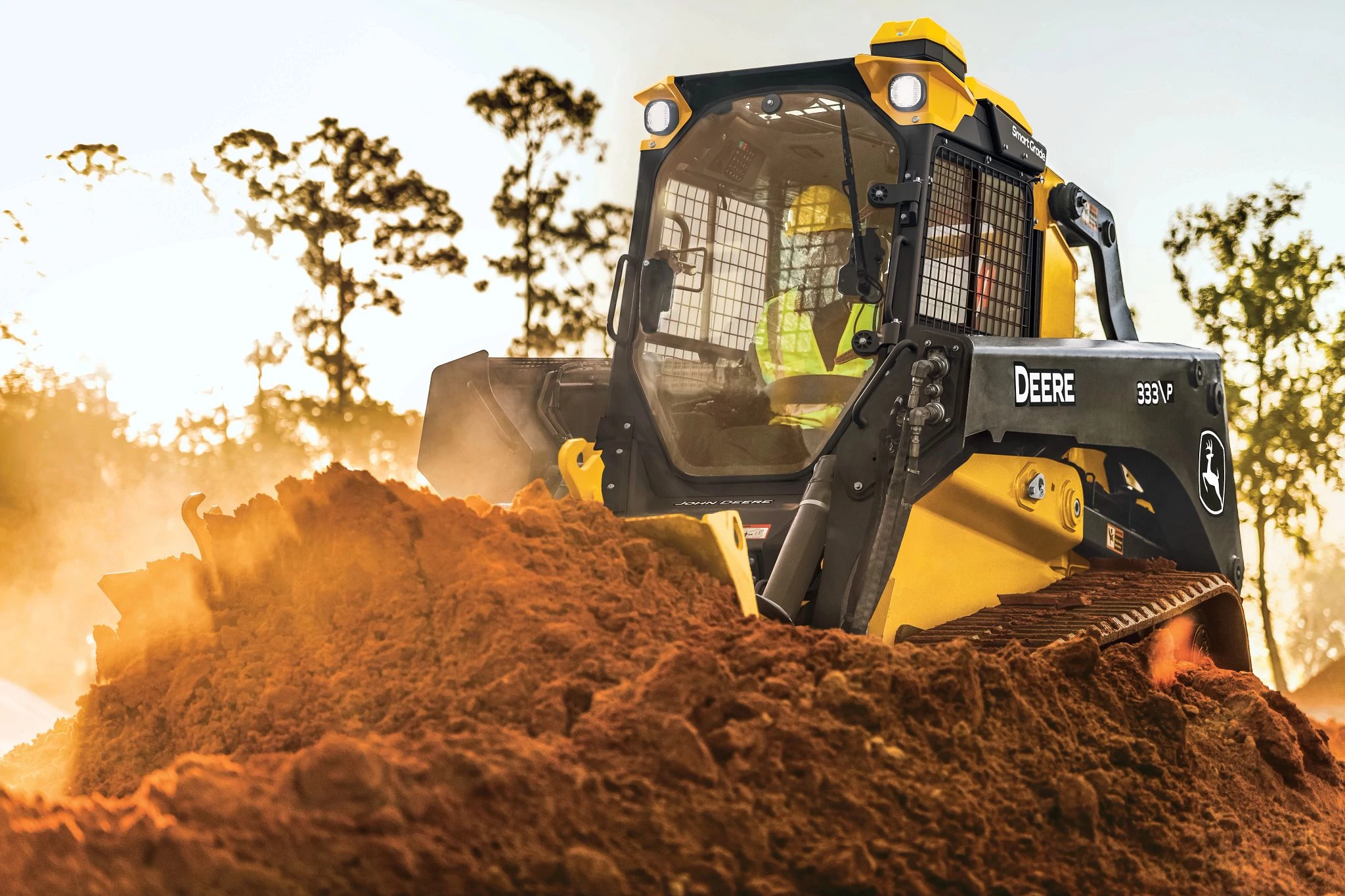 A 330 P skid steer pushes a large mound of reddish soil inside a dirt worksite.
