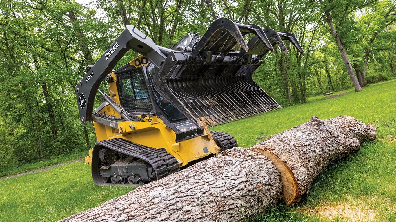 333 P-Tier compact track loader using John Deere grapple attachment to move large log.