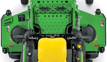 Top‑down view of zero‑turn mower showing the operator area with a yellow seat, control levers, perforated deck surface, and twin mower housings on either side.