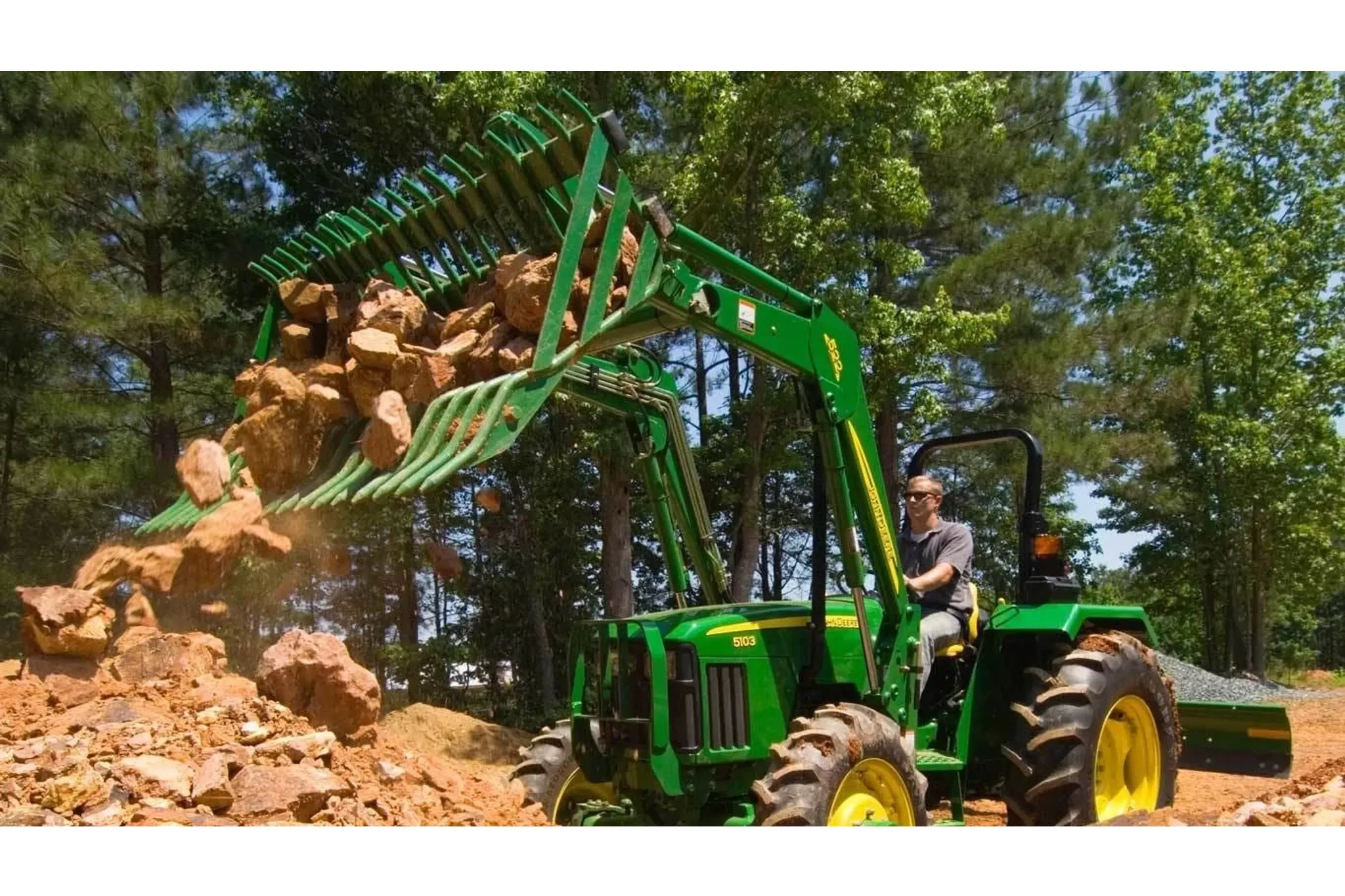 Frontier AR10 Rock Bucket attachment on a tractor dumping boulders