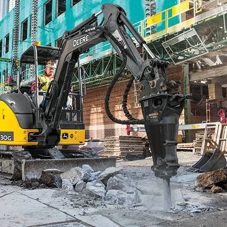 Hydraulic hammer breaking up concrete in the street in front of a building under construction