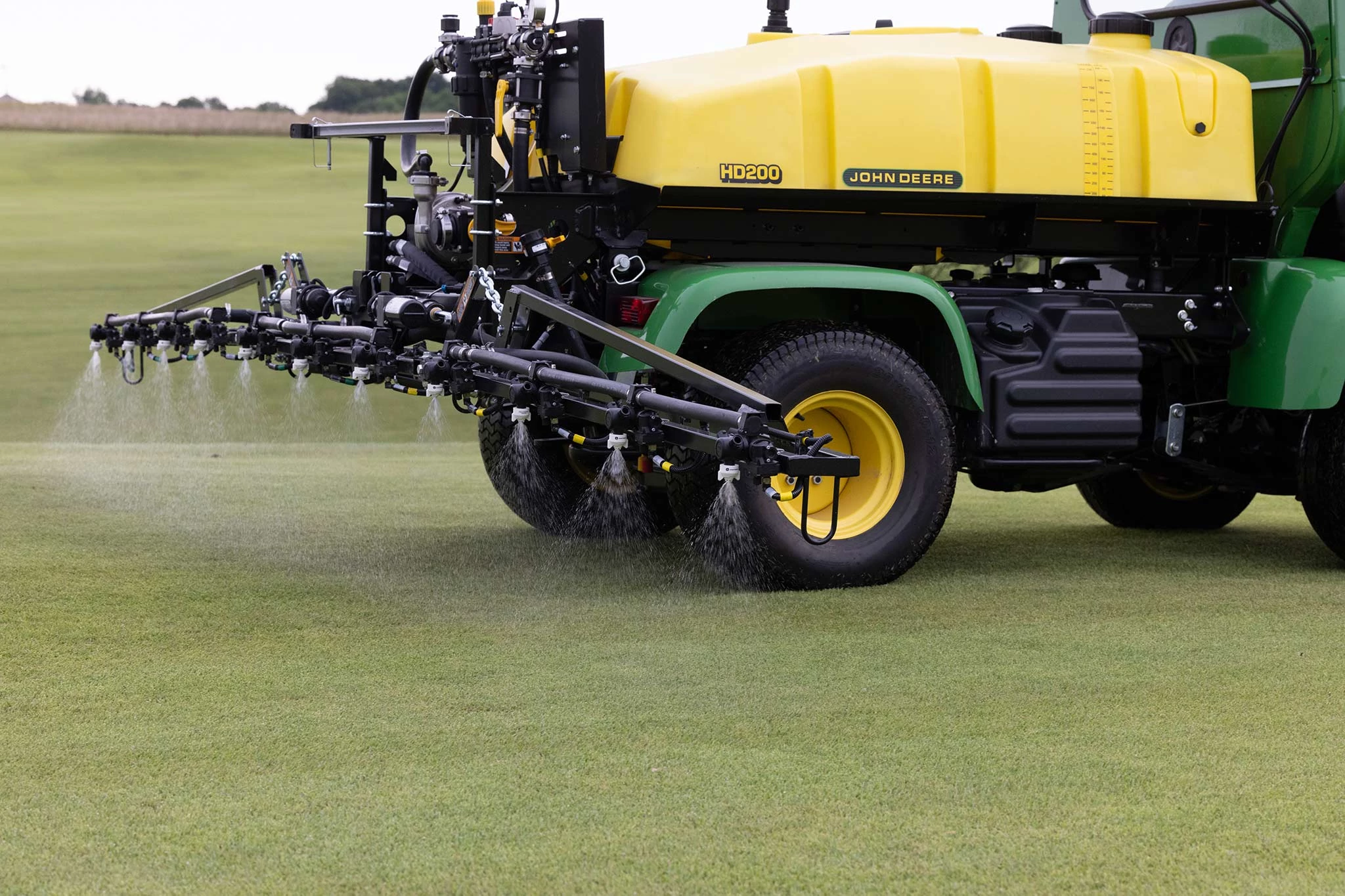 Side right view of the rear 3/4ths of a 2020A ProGator with yellow spray tank spraying a golf green