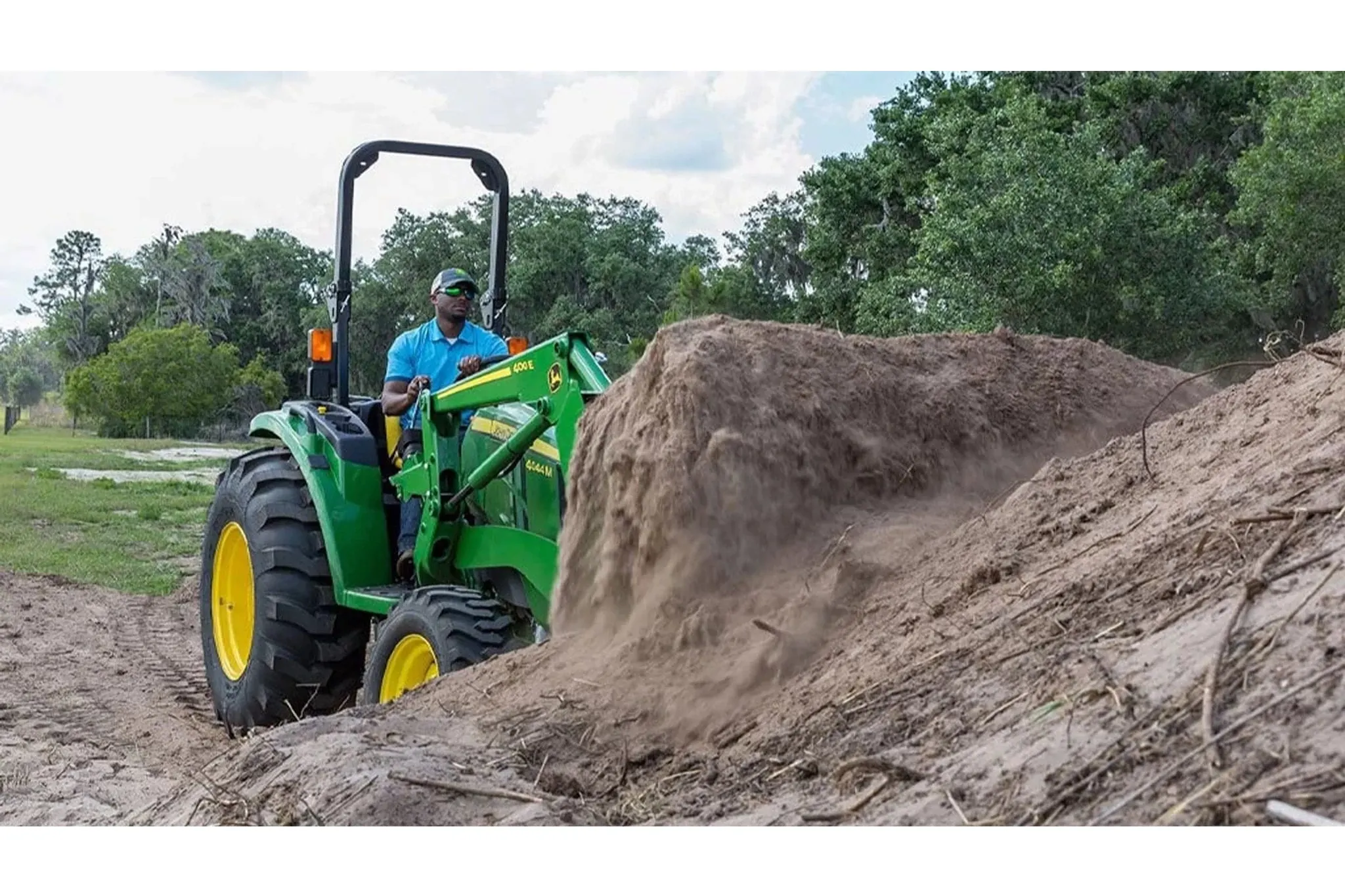 farmer operating a 4044M Compact Tractor to move dirt
