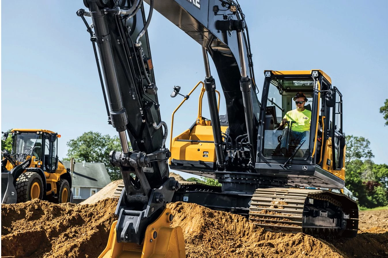 Front view of a 210 P-Tier Excavator scooping dirt on a job site