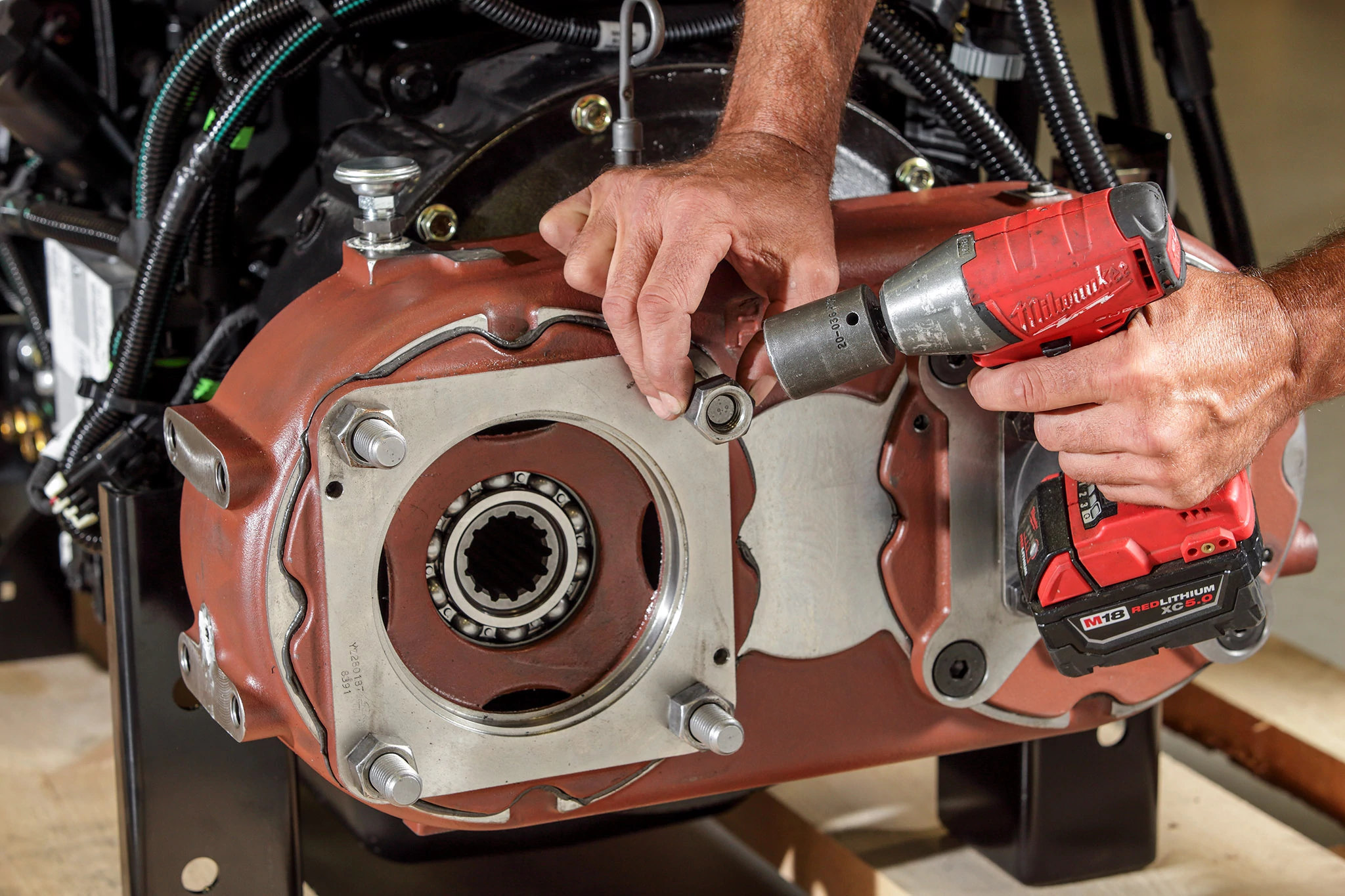Front right view of a pump drive being configured by two hands using a cordless, red impactor