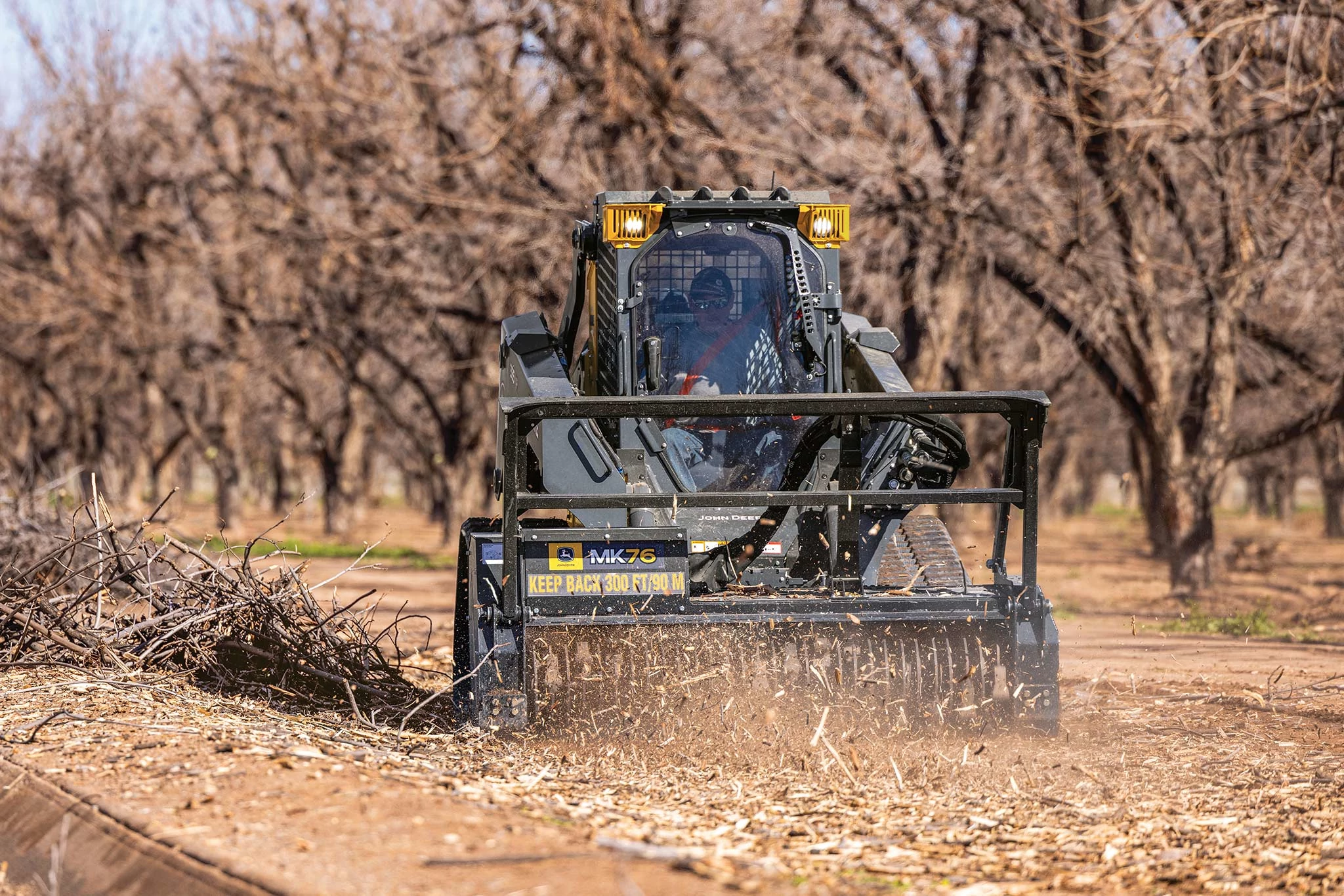 Front view of a 335 P-Tier compact track loader mulching brush with an MK76 mulching head