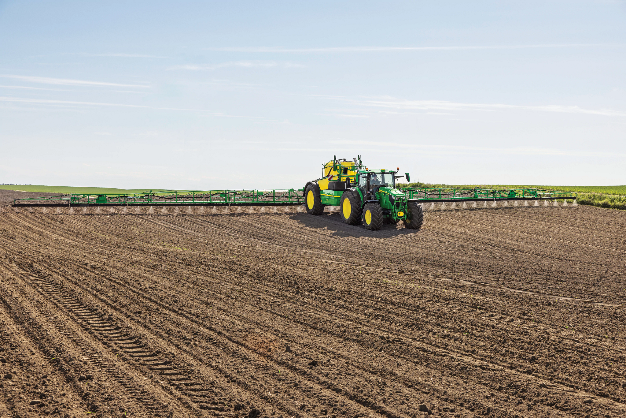 Tractor pulls sprayer in field
