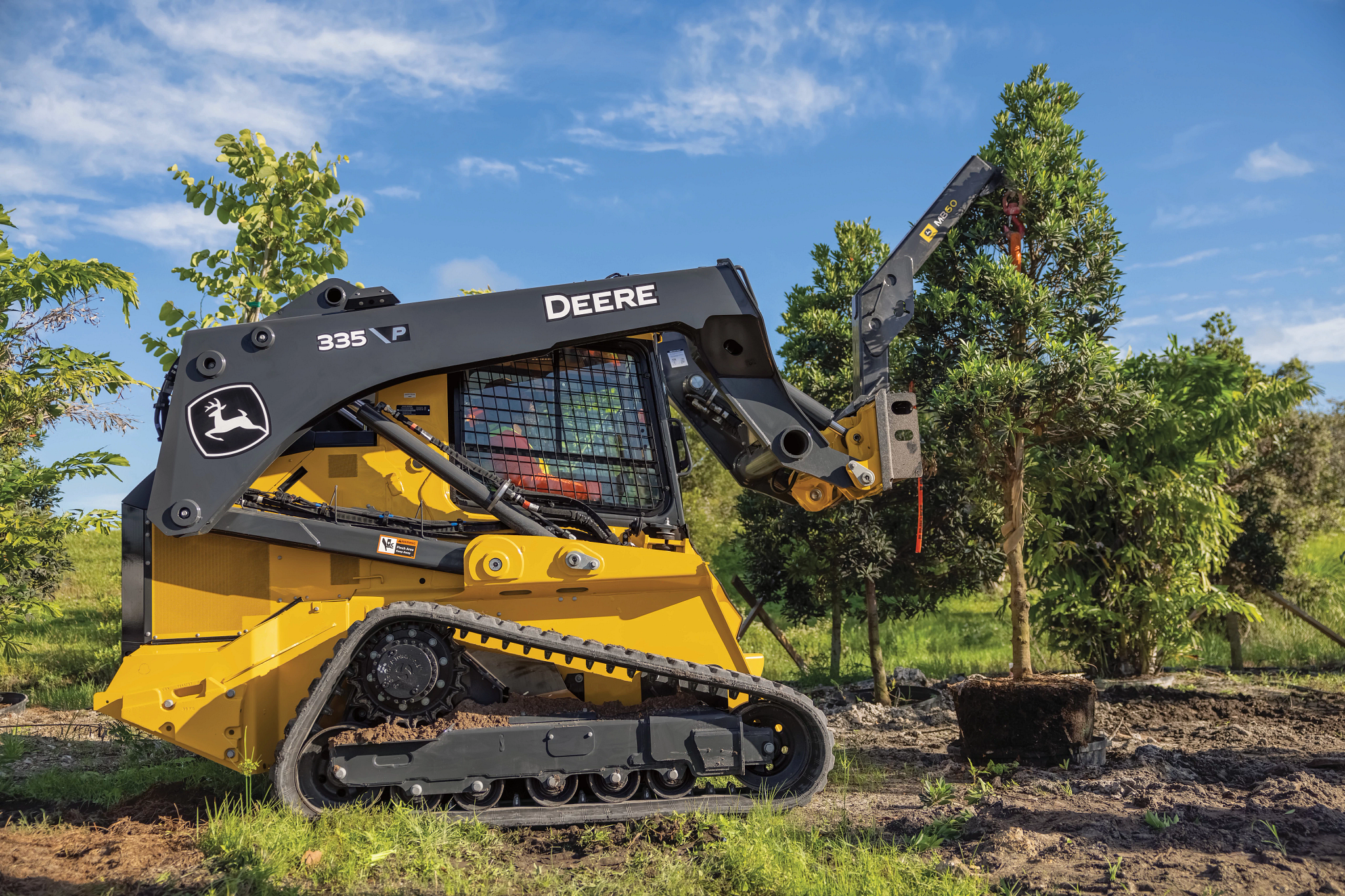 Side right view of a 335 P-Tier compact track loader handling a tree with an MB60 material boom