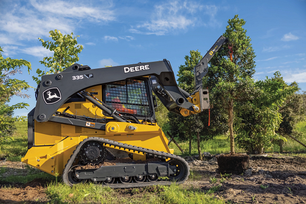 Side right view of a 335 P-Tier compact track loader handling a tree with an MB60 material boom