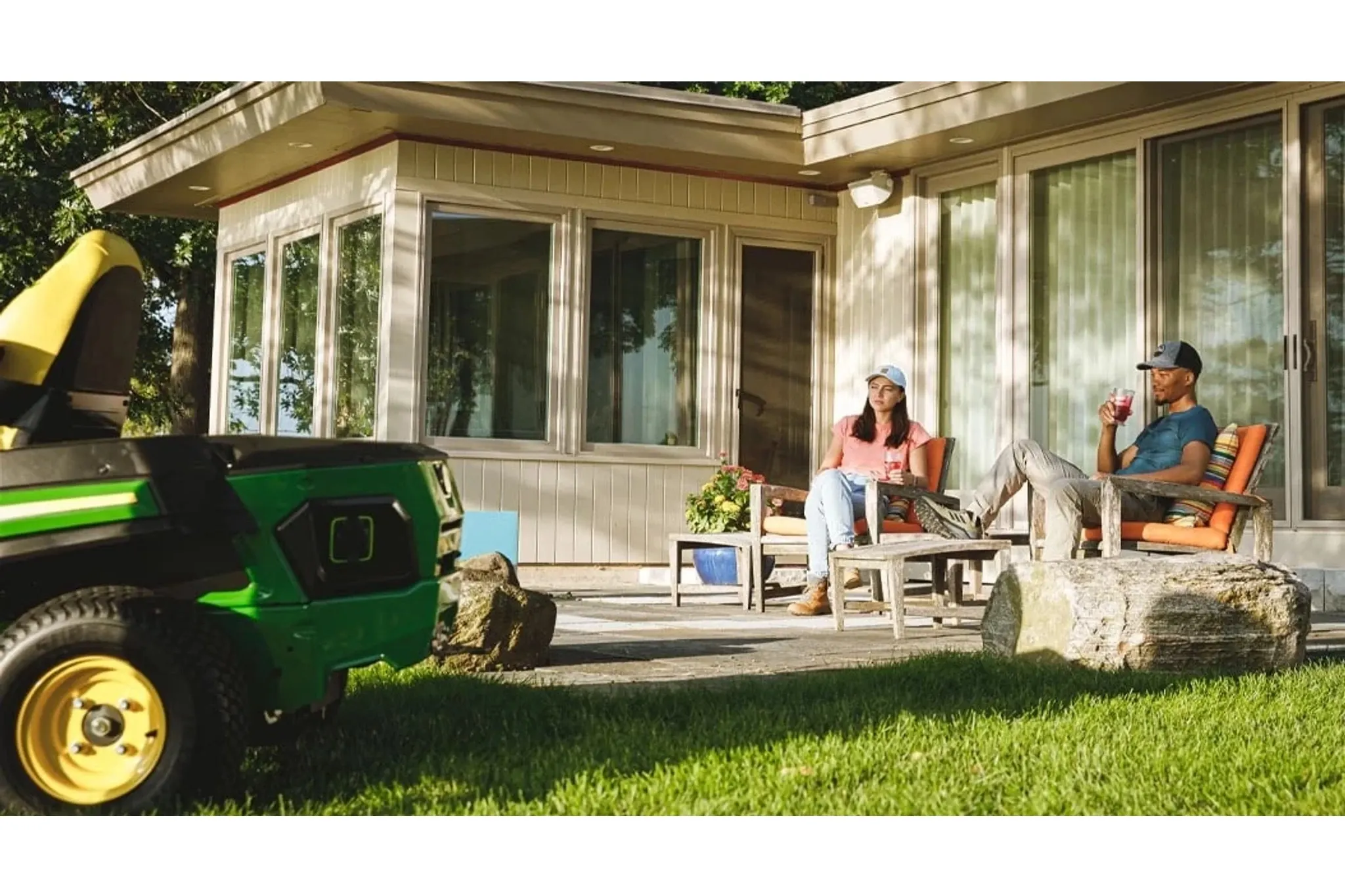 Two homeowners sitting on a patio with drinks with a utility vehicle in the foreground