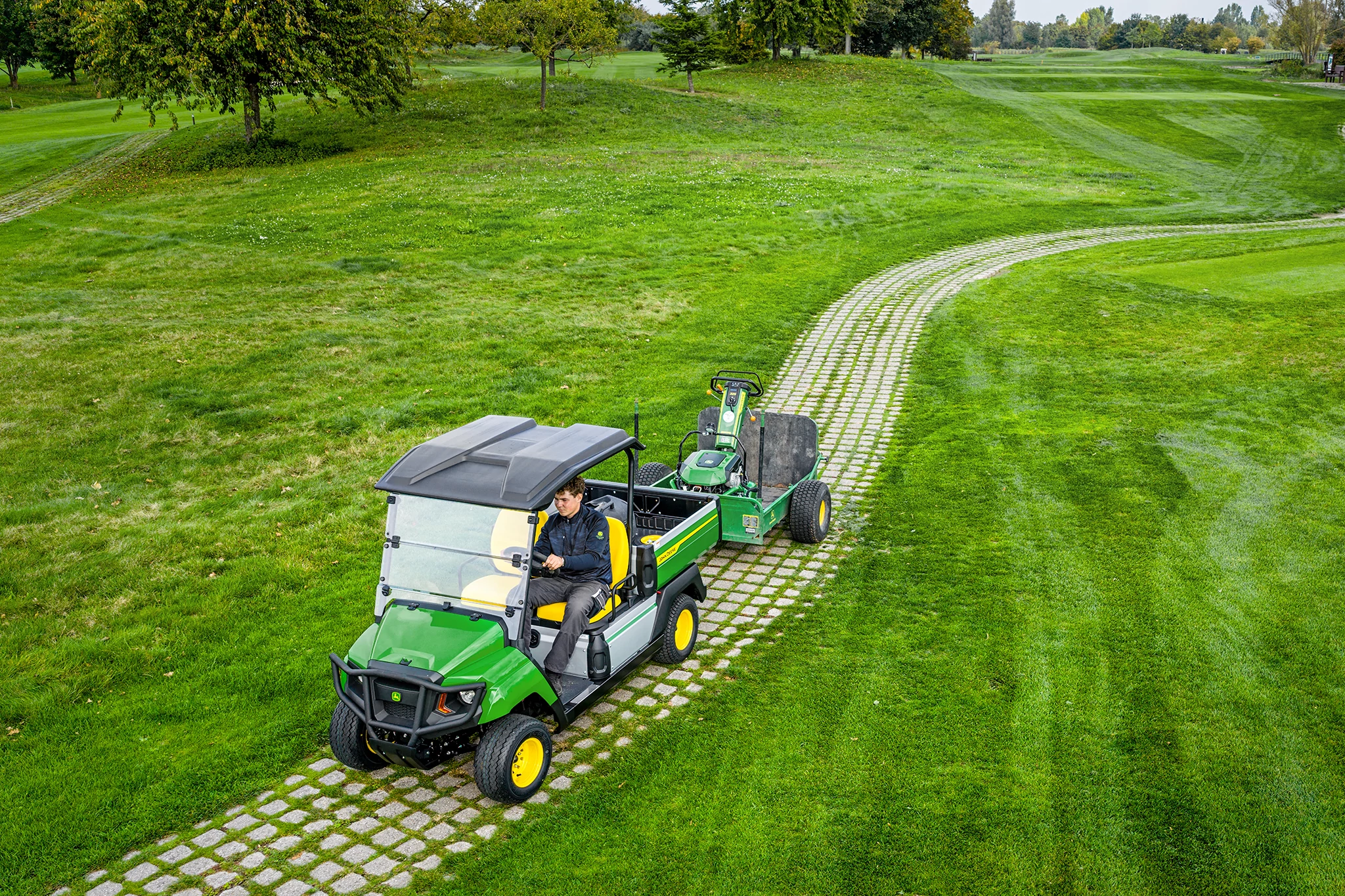 John Deere Gator GS towing equipment on a grassy golf course path