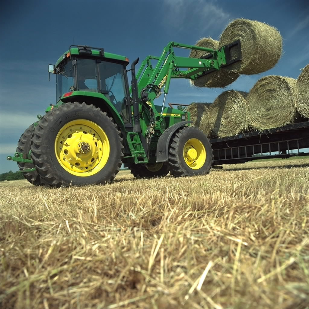 Tractor loading bales in field
