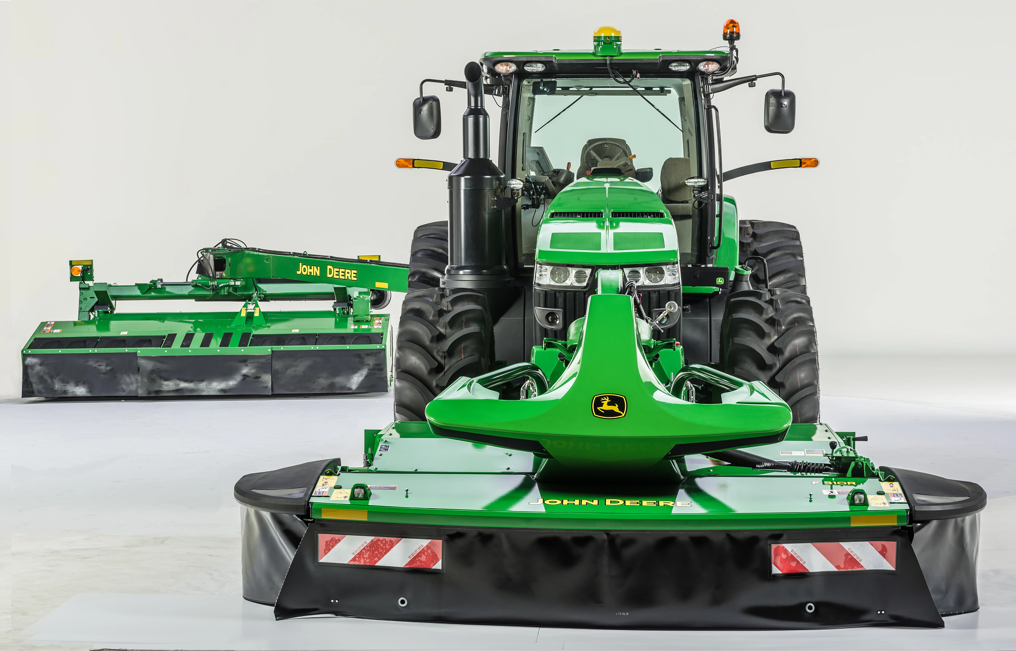 Front studio view of an 8R Tractor with F310R Front Mount and 900-Series Rear-Mount Mower-Conditioners attached